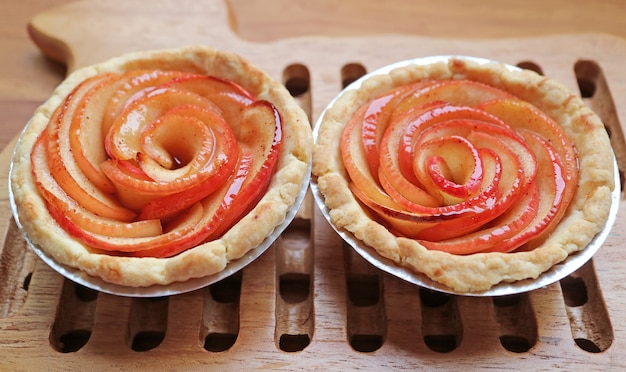 나무 브레드 보드에 신선한 구운 수제 미니 애플 로즈 Tartlets의 쌍