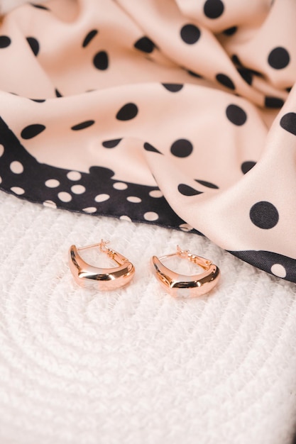 A pair of gold earrings with a black polka dot background