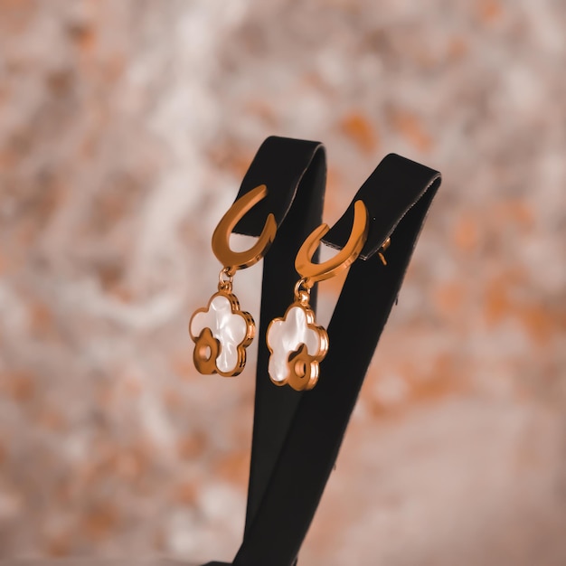 A pair of gold earrings with a white and gold flower design.