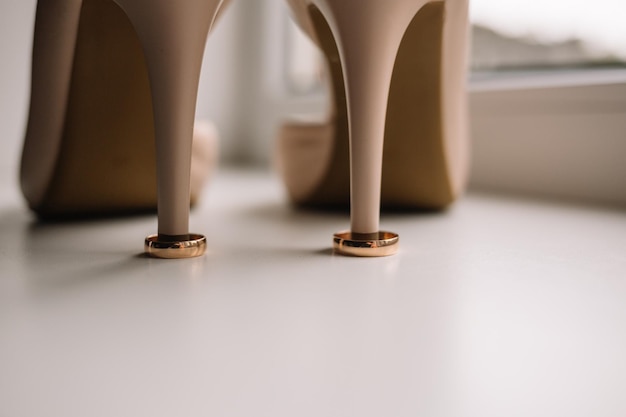 結婚式のクローズアップマクロの準備の花嫁の白い靴の詳細に金の指輪のペア