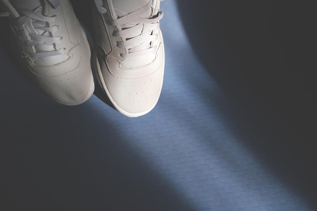 A pair of gray leather sneakers on a blue fitness gym mat