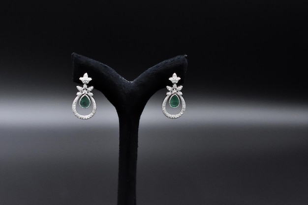 A pair of green stone earrings with a diamond and emerald.