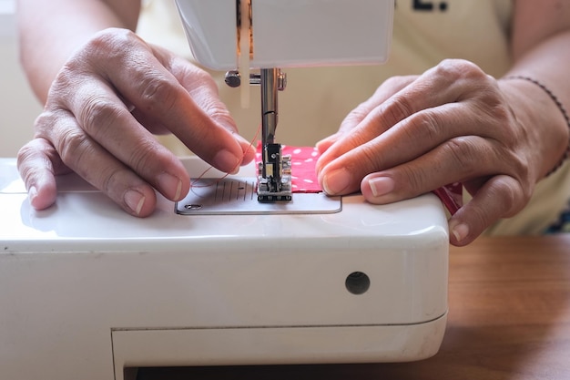 Photo pair of hands working on a sewing machine