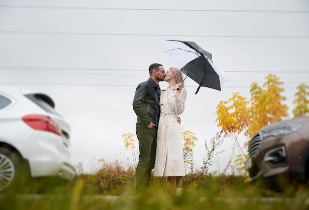Pair kissing on road between two cars outdoors