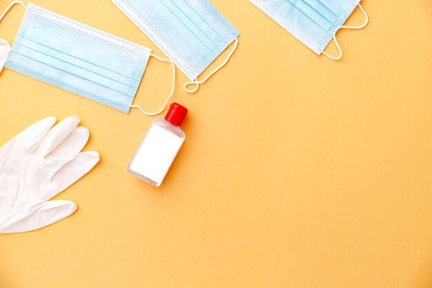 Pair of latex medical gloves and surgical ear-loop mask on orange background. Protection concept