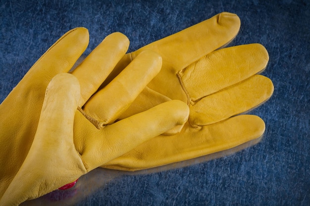 Pair of leather protective gloves on scratched metallic background construction concept