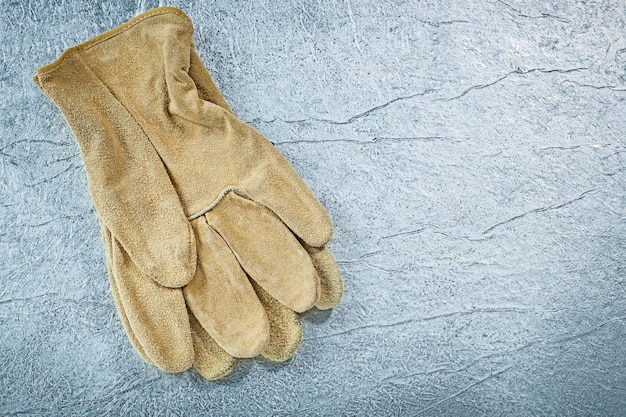 Pair of leather safety gloves on metallic surface construction concept