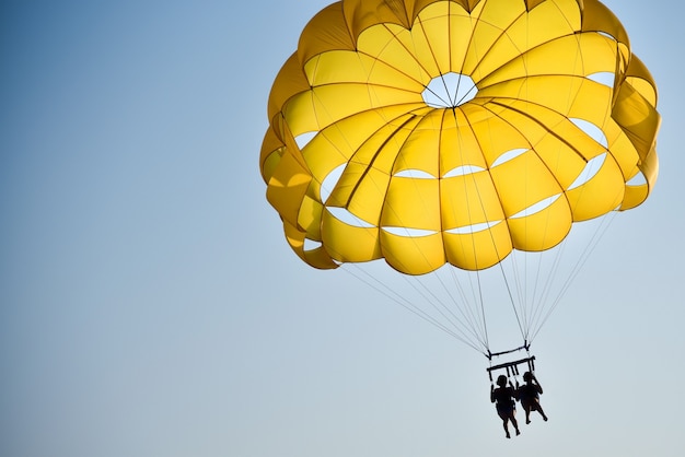 A pair of lovers flies on a parachute over the sea at sunset