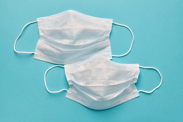 Pair of medical disposable masks on a turquoise background