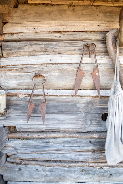 A pair of metal scissors are hanging on a wooden wall.