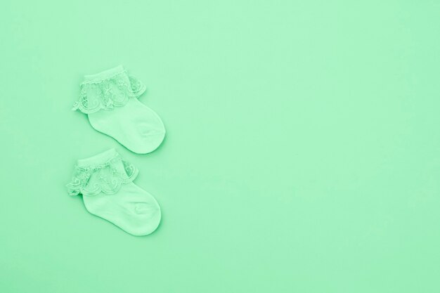 Pair mint green cute baby socks on blue background. Baby accessories. Flat lay.