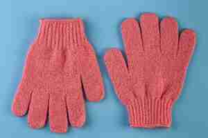 Photo a pair of pink massage gloves for shower on blue background