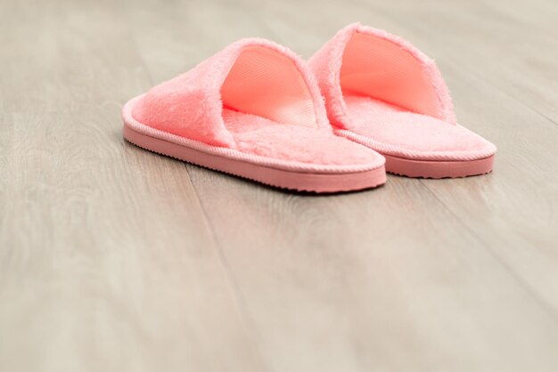 Pair of pink slippers on wooden floor