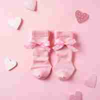 Photo a pair of pink socks with bows and hearts on a pink background