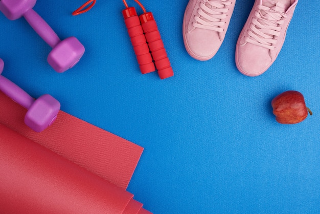 Pair of pink training sneakers with laces, purple plastic dumbbells