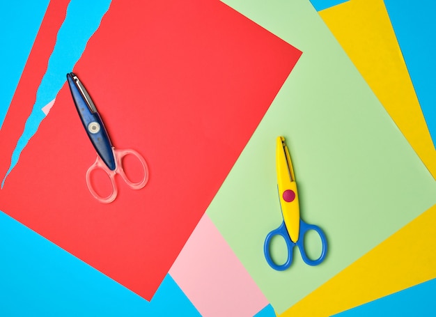 Photo pair of plastic scissors and colored paper for cutting figures