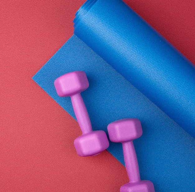 pair of purple plastic dumbbells on a blue neoprene mat