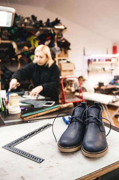 A pair of readymade stylish shoes on the background of a master who is engaged in the design and manufacture of leather shoes in the shop