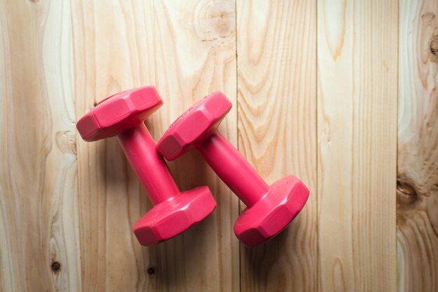 Pair of red 1 kg dumbbells on wood