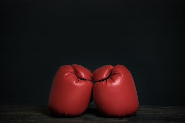 Photo pair of red boxing gloves on a black background. copy space