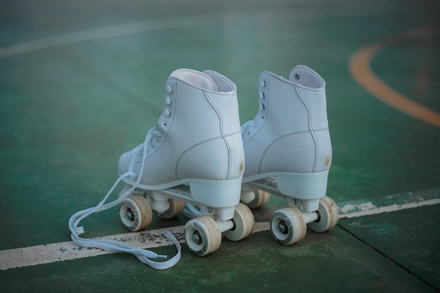 Pair of roller skates with untied laces on a green court