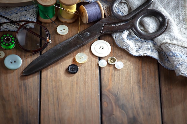 A pair of scissors sits on a table next to a pair of glasses.