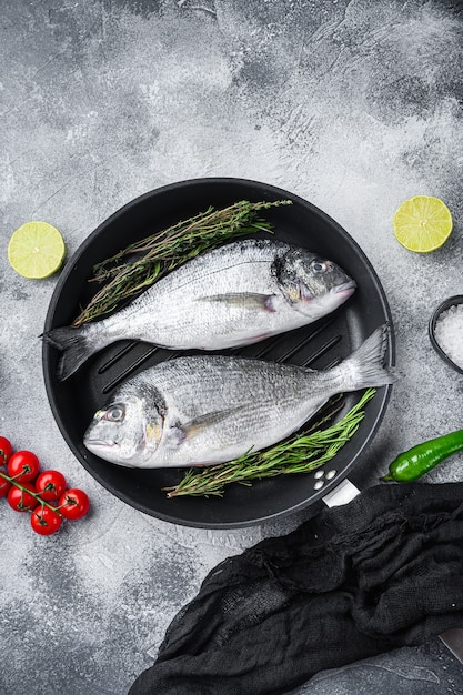 Pair of Seabream or dorado raw fish on grill pan with ingredients