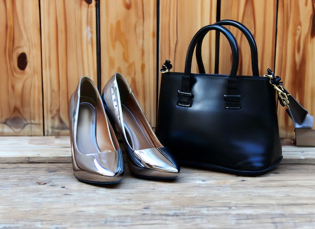 A pair of shoes and a bag sit on a wooden floor.