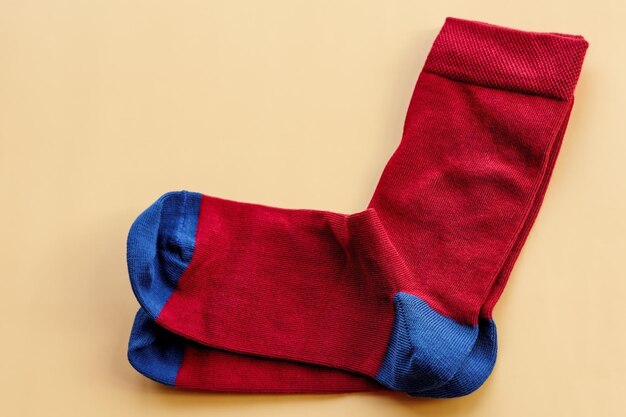 A pair of socks on a beige background Red and blue knitted socks