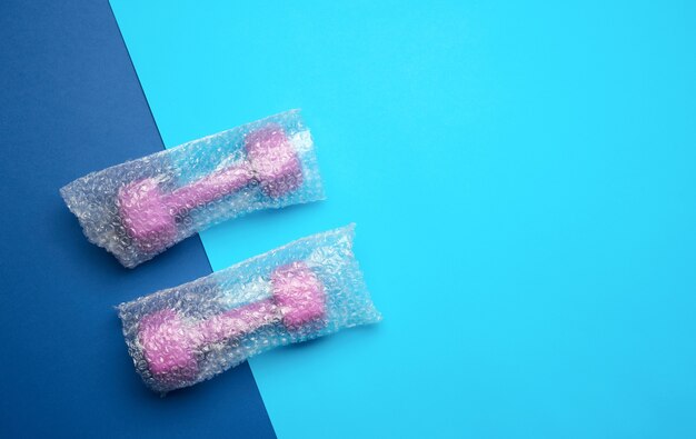 A pair of sports purple dumbbells in a transparent bag