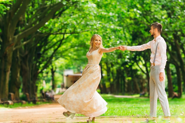 Un paio di abiti eleganti che ballano in un parco sullo sfondo di alberi