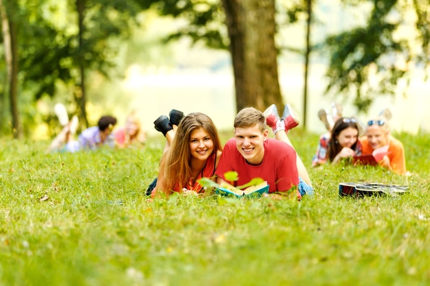 Photo pair successful students with a textbook in a park