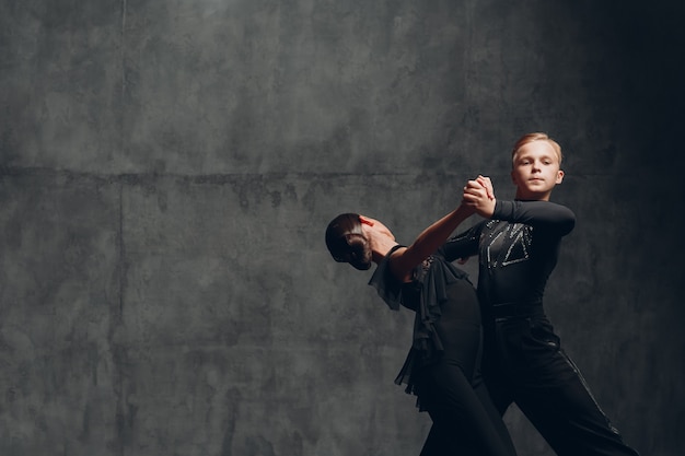 Coppia ballerini di tango in costume nero che ballano nella sala da ballo.