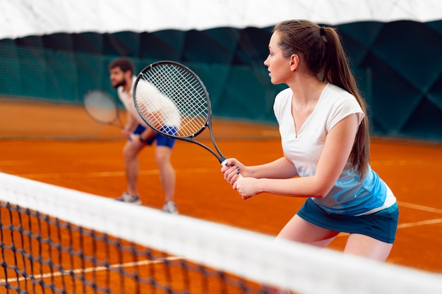 Pair of tennis players, man and woman waiting for service at indoor court