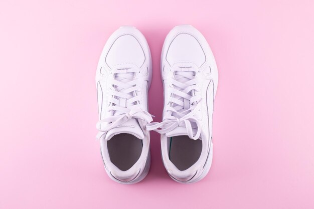 Pair of trendy white sneakers on light pink background flat lay Space for text