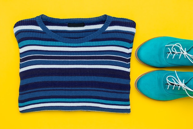 Pair of turquoise suede shoes. Demi-season aqua oxfords with white laces and knitted striped women's pullover on a yellow background