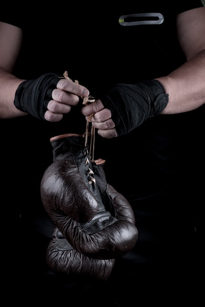 Pair of very old boxing sports gloves in men's hands