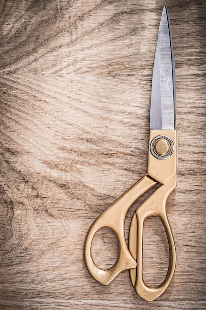 Foto coppia di forbici dorate chiuse vintage su tavola di legno