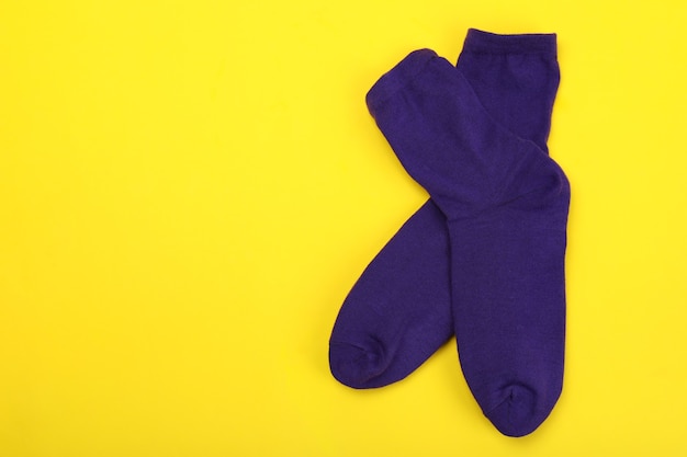 Pair of violet socks on yellow background