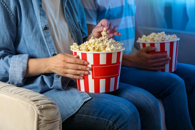 Pair watching film on sofa and eating popcorn