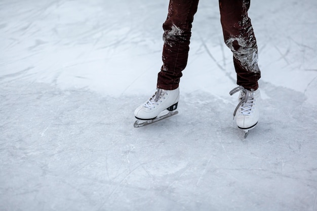 A pair of white figure skates with laces on frozen ice closeup A woman or girl is skating