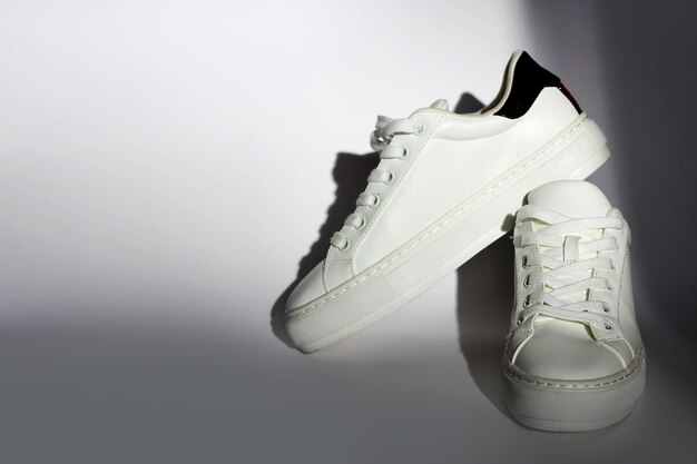 A pair of white modern sneakers on a colored fashionable background the concept of comfortable universal shoes for everyone