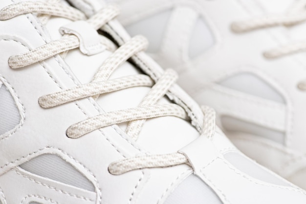 Photo pair of white sneakers with shoelaces closeup