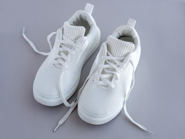 pair of white summer sneakers on a gray background fashionable stylish sports casual shoes