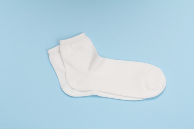 Pair of white women socks on a blue background, Top view.