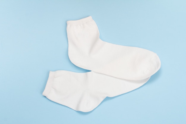 Pair of white women socks on a blue background, Top view.