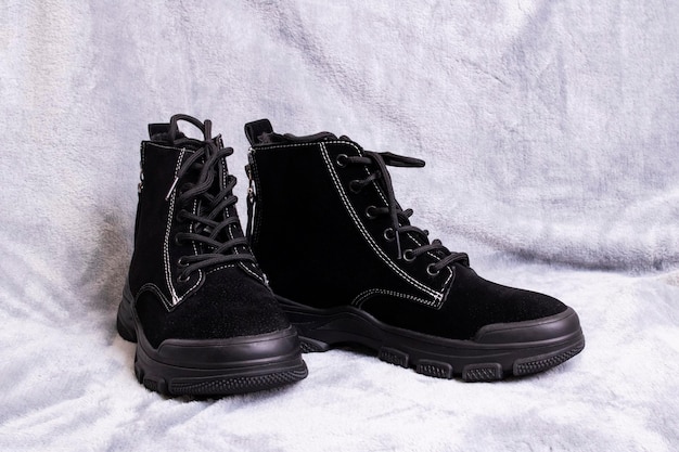 Pair of womens black boots on gray background