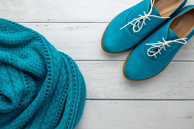 Pair of womens low shoe and blue pullover on light wooden background. Flat lay, modern trends of fashion clothes. Top view. Casual style concept.