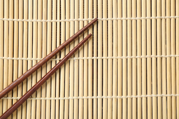 Pair of wooden chopsticks on bamboo mat top view Space for text