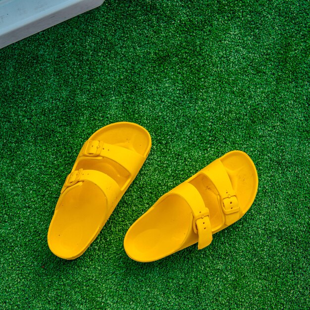 A pair of yellow sandals are on a green lawn.